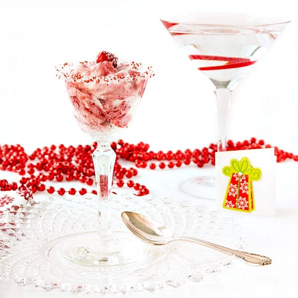 A glass of red and white fool on a cut glass plate. Glass is rimmed with red and white sugar.