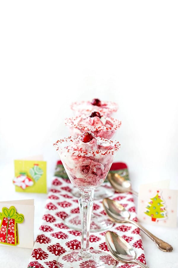 Cranberry fool made with whipped cream and cranberry sauce in cut glass wine glasses that are rimmed with sugar.