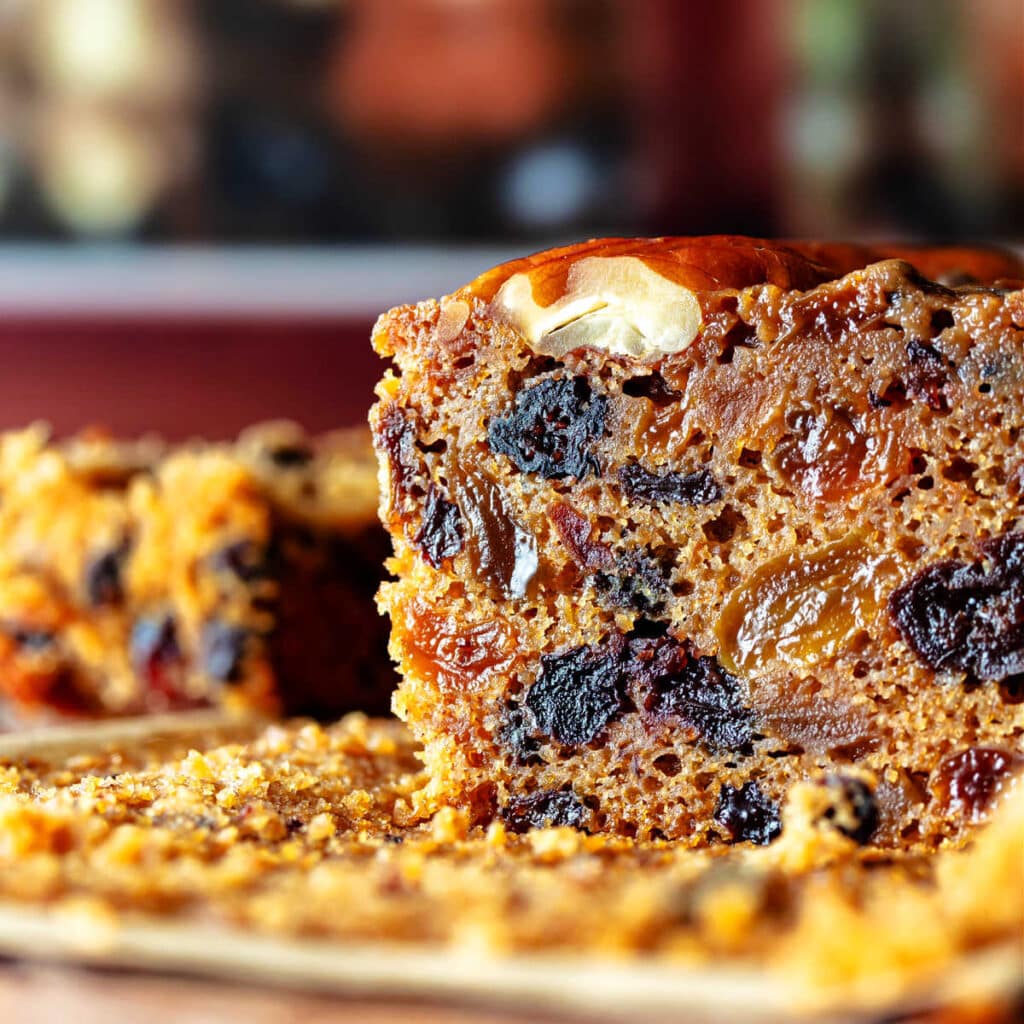 A closeup of a slice of fruitcake showing all the dried fruit inside.