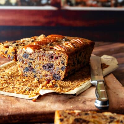 A sliced fruitcake made with lots of dried fruit and without candied fruit on a cutting board.