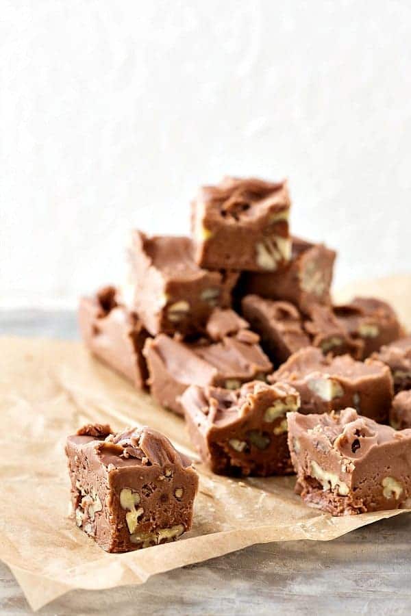 A stack of fudge with walnuts on a piece of parchment paper.