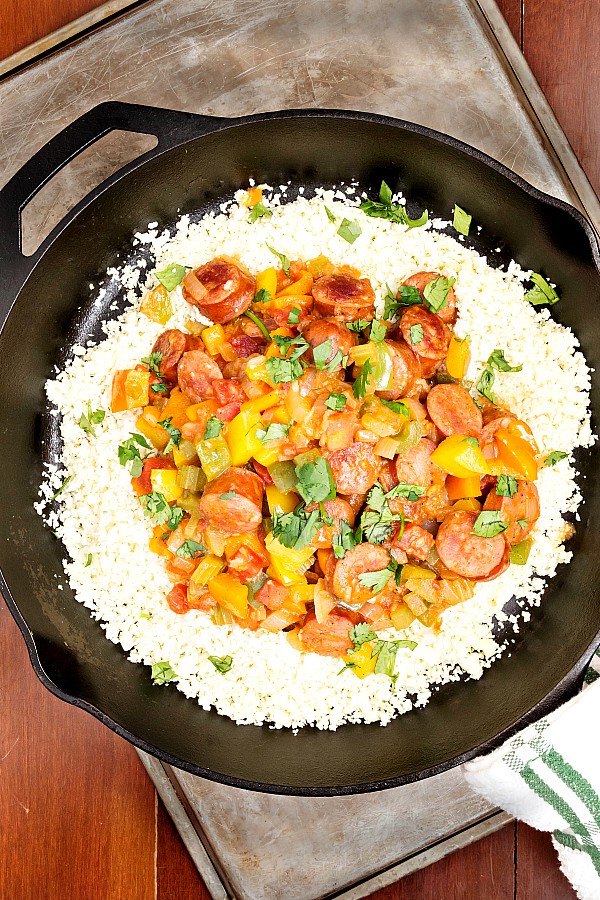 An overhead shot of Aidells andouille sausage cooked with peppers over cauliflower rice.