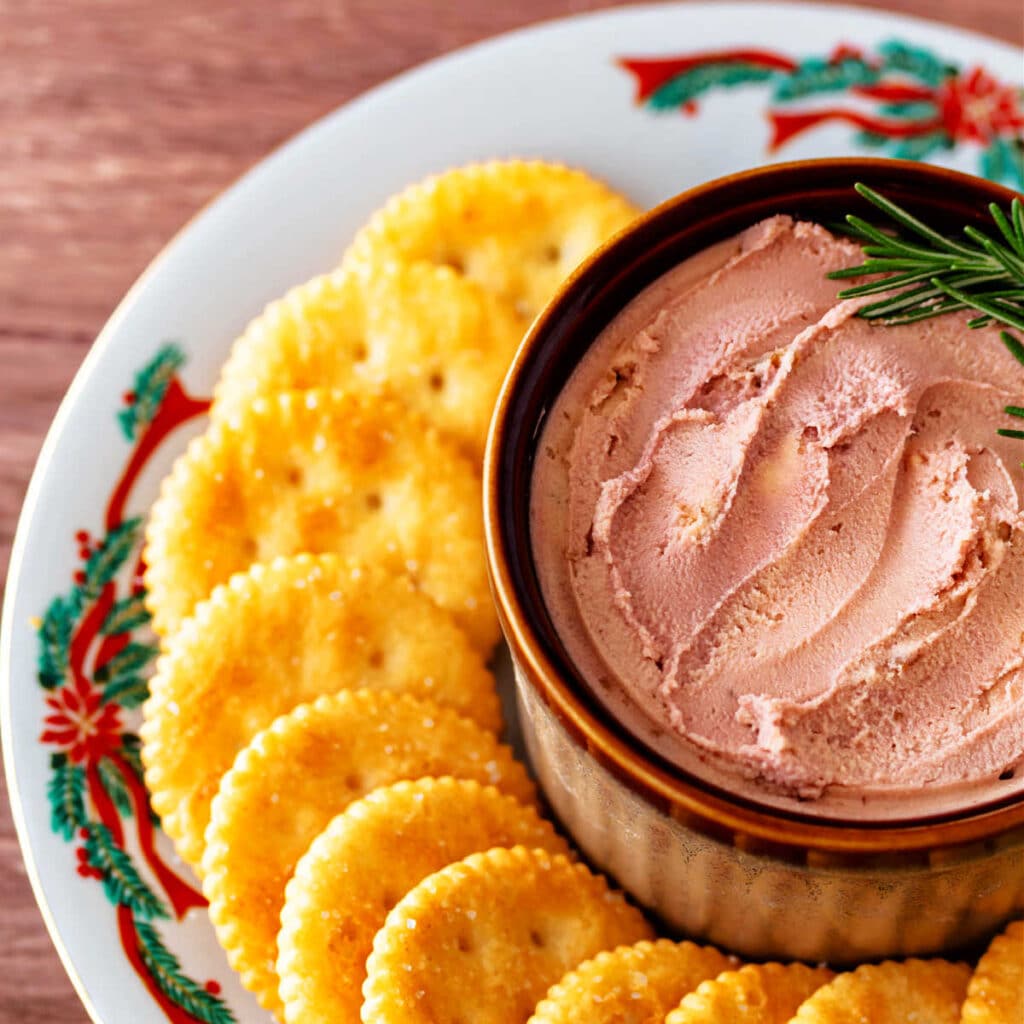 An overhead shot of a brown crock filled with port wine cheese spread and surrounded by Ritz crackers.