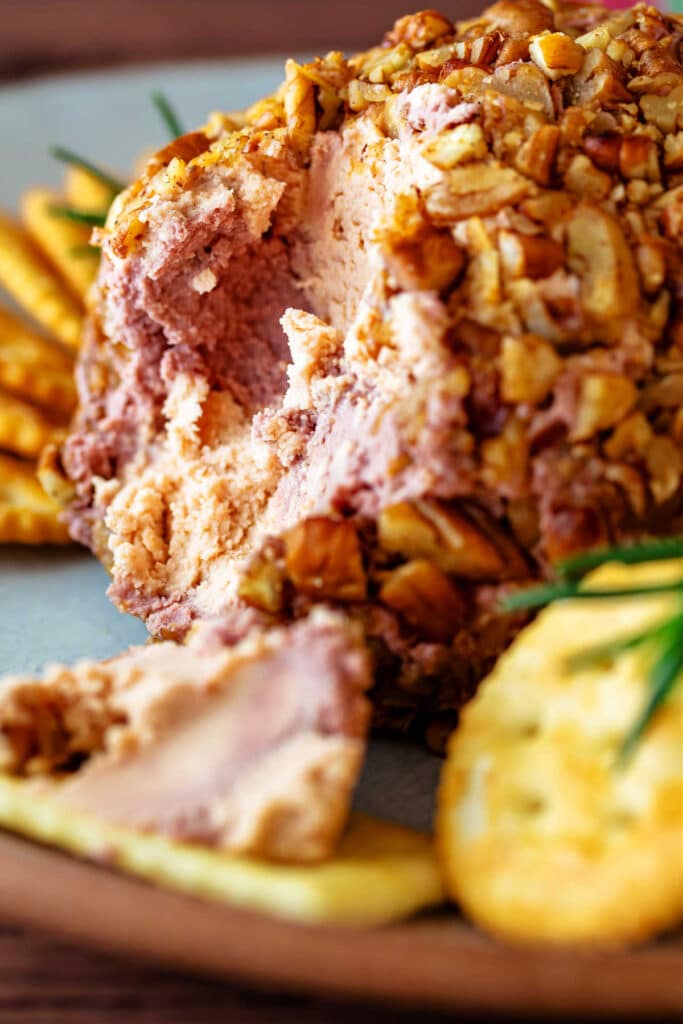 A close up of a cheese ball that has been cut into showing some cheese on a cracker and the orange and purple swirls on the inside.