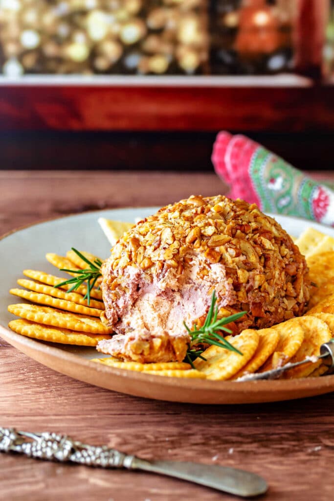 A port wine cheese ball on aplate with crackers and sprigs of rosemary.