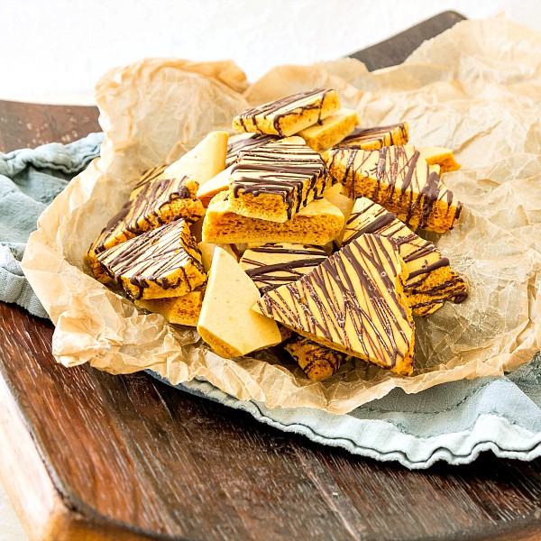 Wax paper with stacks of bourbon honeycomb candy drizzled with chocolate.