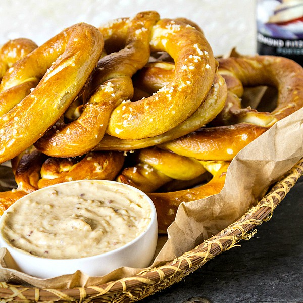 Basket of homemade soft pretzels with a small ramekin of dip.