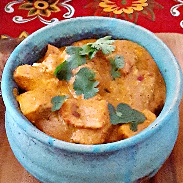 Close up of blue pottery bowl with tikka masala with homemade paneer.