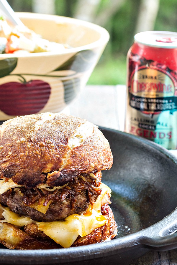 Got to be NC burger with cheese and pulled pork on a bun in a cast iron pan next to a can of Cheerwine soda. 