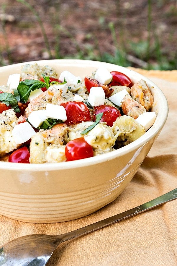 A large pottery bowl filled with tortellini caprese salad.