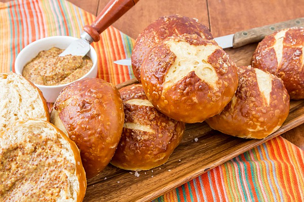 A wooden platter of baked pretzel buns. Ready for serving.