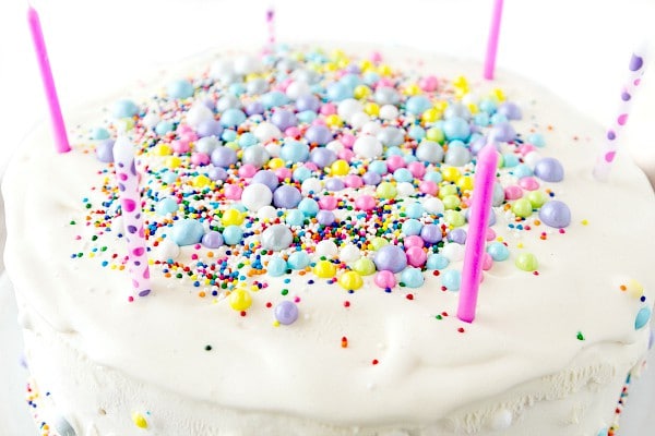 The top of an ice cream cake decorated with edible pearls and sprinkles and birthday candles.