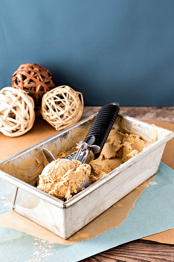 Metal loaf shaped container of homemade caramel vanilla ice cream with an ice cream scoop.