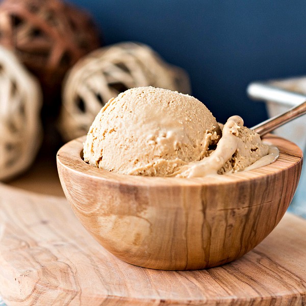 Wooden dish of ice cream with a spoon.