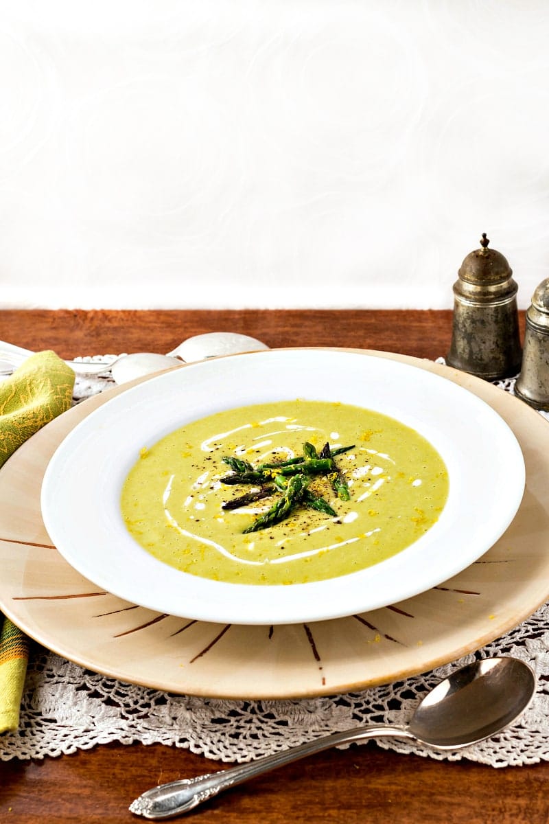A soup bowl of creamy lemon asparagus soup garnished with asparagus tips.