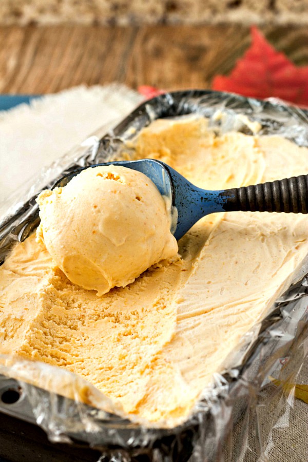 Scooping Orange Cardamom Pumpkin Ice Cream from a loaf pan. 