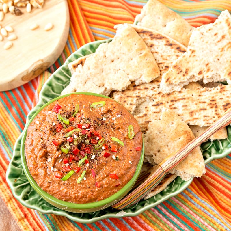 Middle eastern walnut dip in a bowl with pita on a platter.