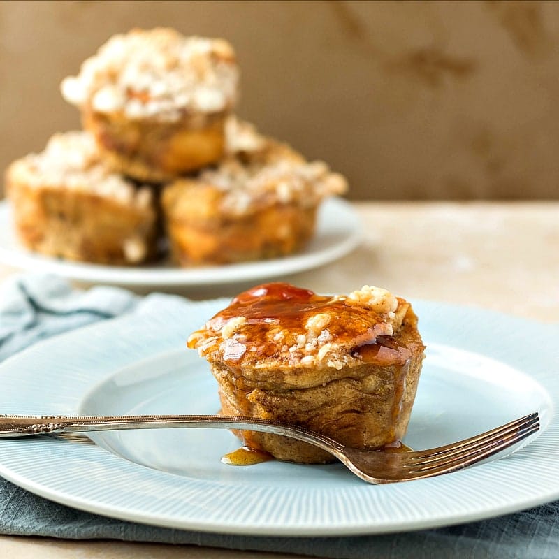 One Hawaiian Roll French Toast Muffins on a plate with a stack of them in the background.