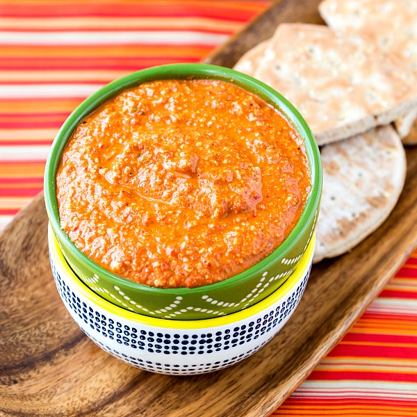 A bowl of middle eastern walnut dip with sliced pita for dipping.