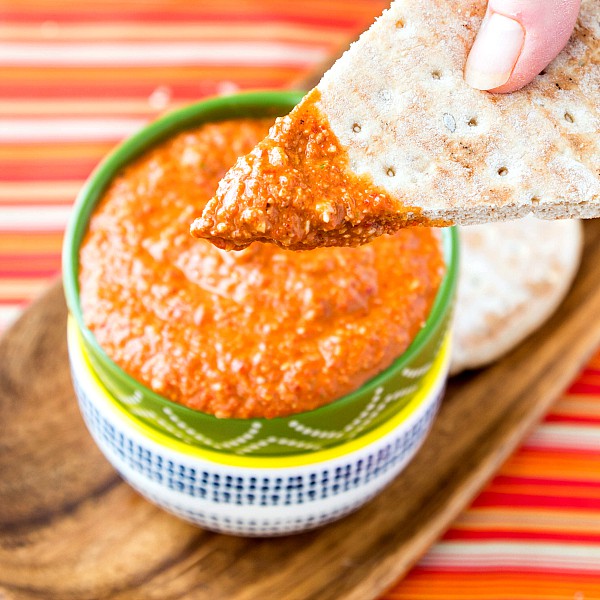 A piece of pita dipped into muhammara.