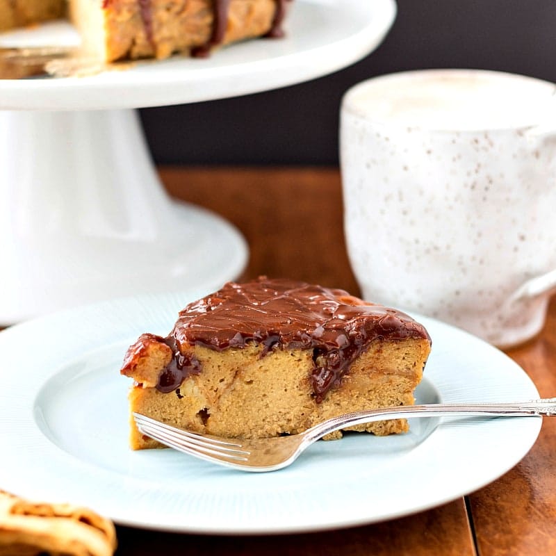 A plate with a triangular slice of chocolate glazed bread pudding with a fork.