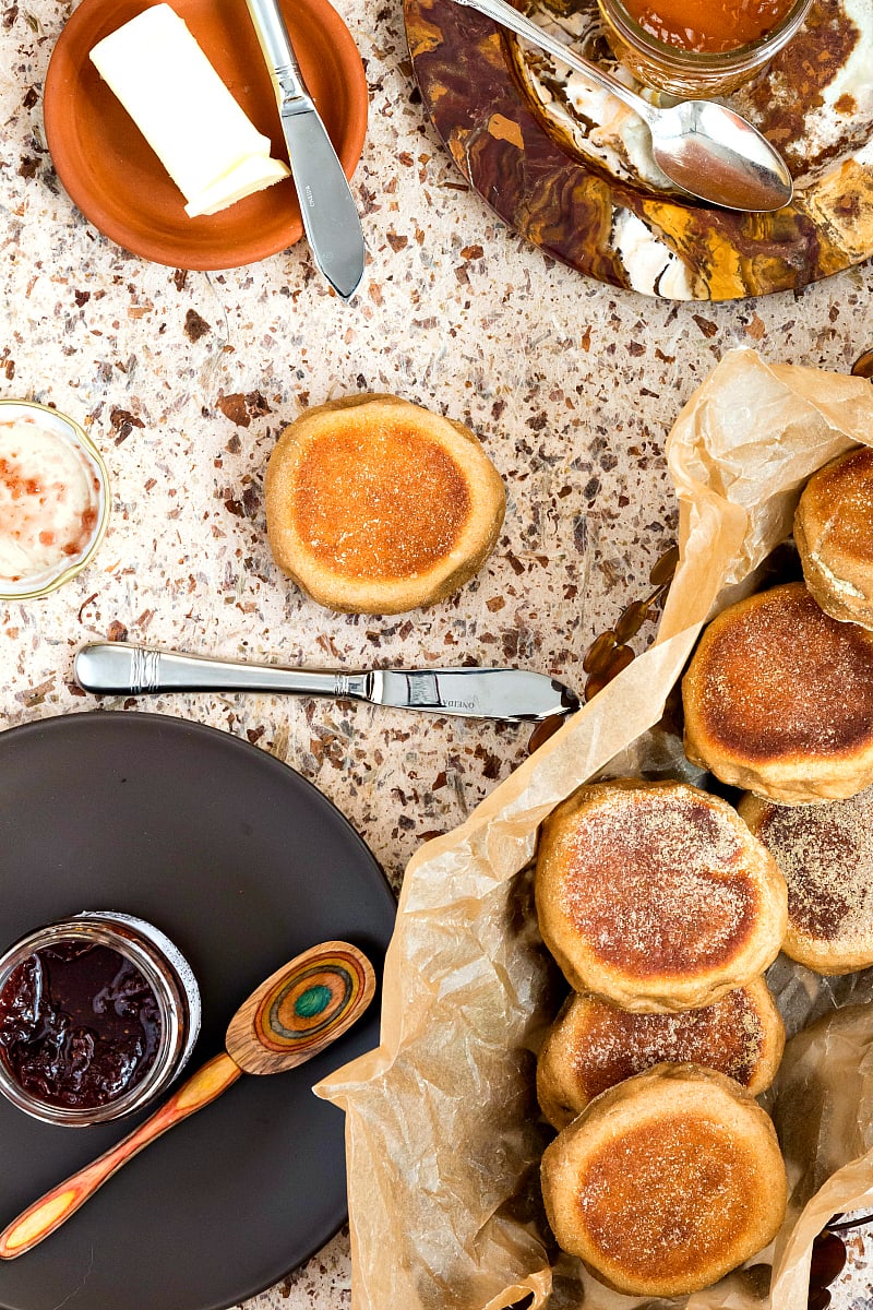Overhead shot of English muffins in a basket, jam, and a butter knife.