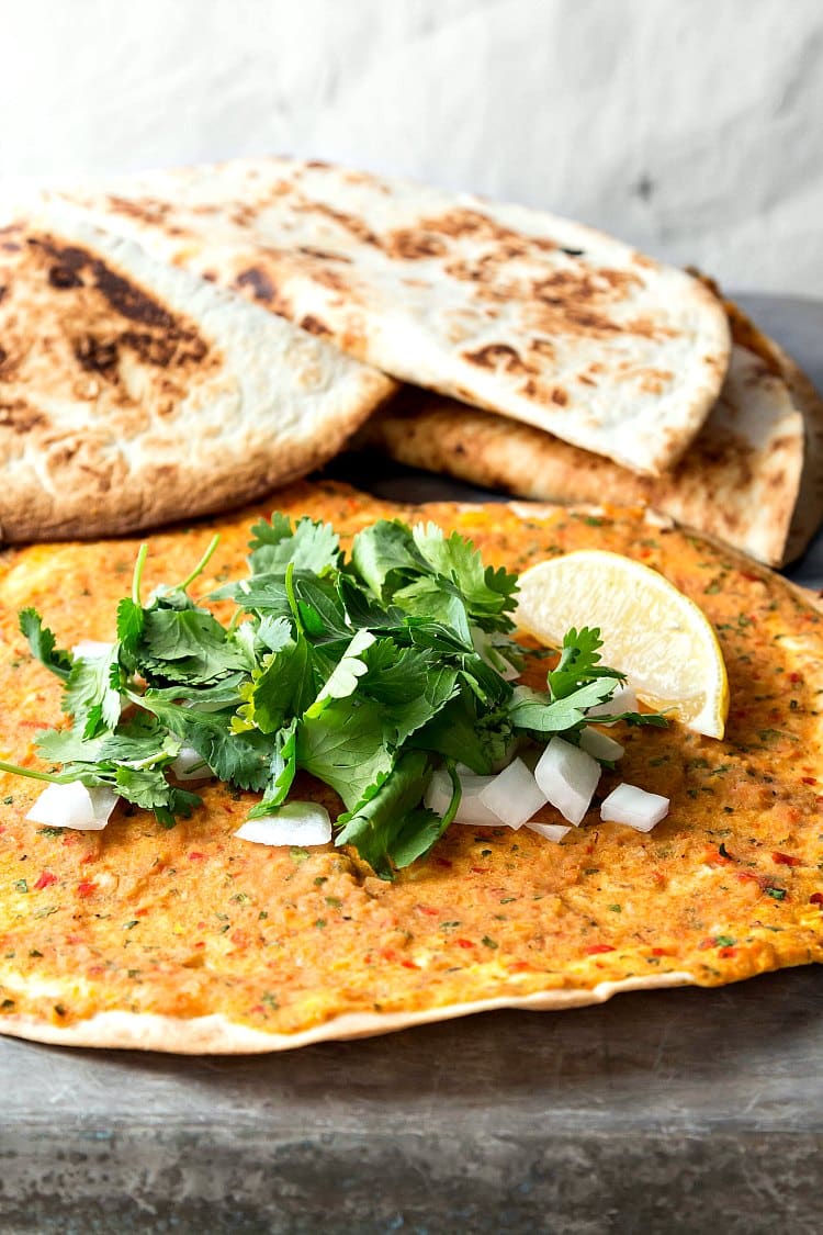 Tortillas spread with vegan hummus, with cilantro and onions on top.