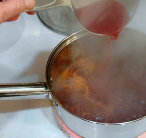 Pouring blood orange juice into caramel to stop the cooking process.