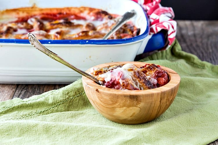 A bowl of cobbler and the baking dish of cobbler in the background.