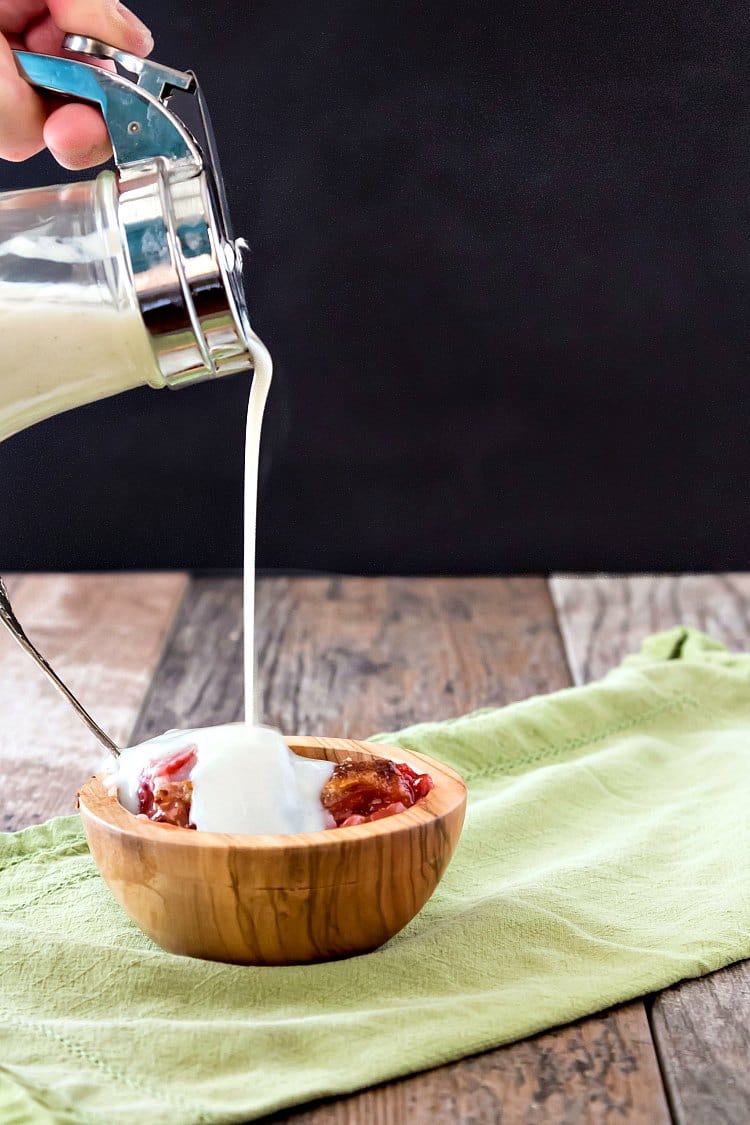 A pour shot of milk dip pouring over a wooden bowl of sonker.