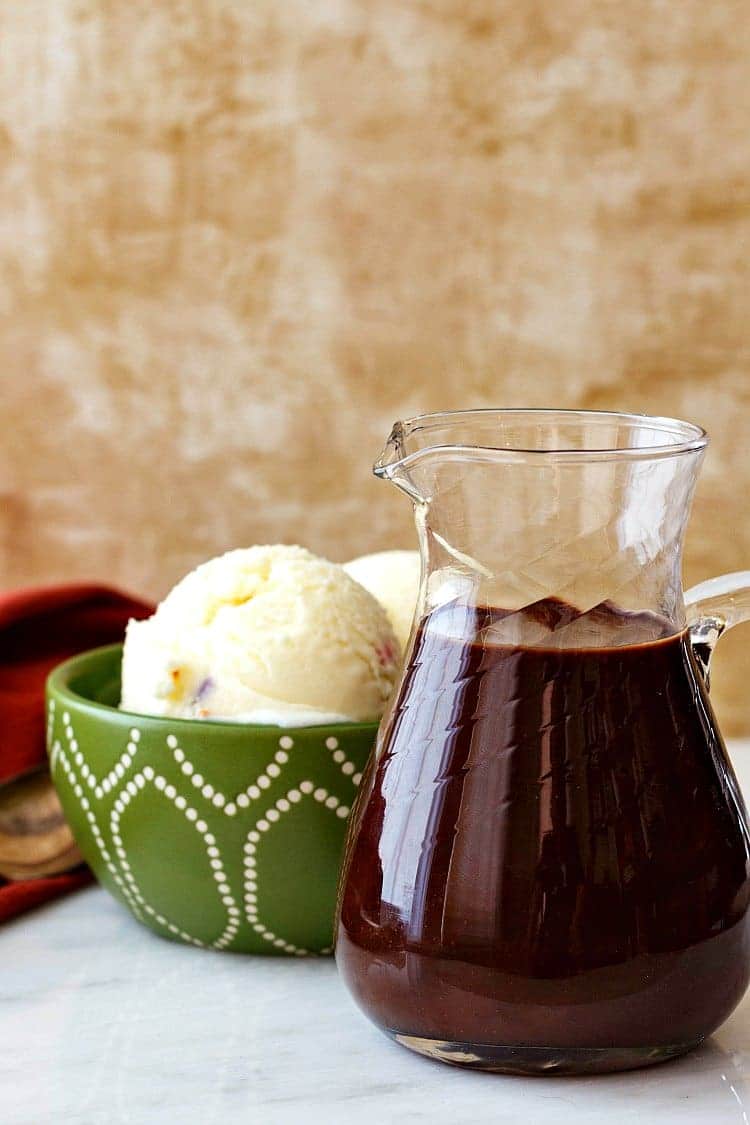 A green bowl of vanilla ice cream and a pitcher of easy fudge sauce.