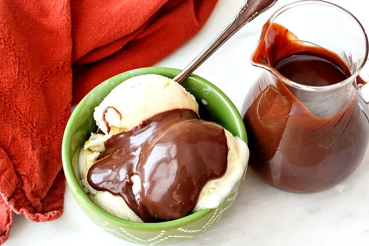 A pitcher of quick hot fudge sauce and a bowl of vanilla ice cream topped with the sauce.