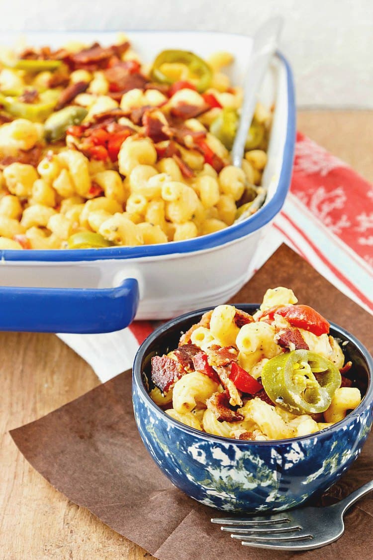 Southern macaroni and cheese recipe topped with crumbled bacon, sweet red peppers, and pickled jalapenos.
