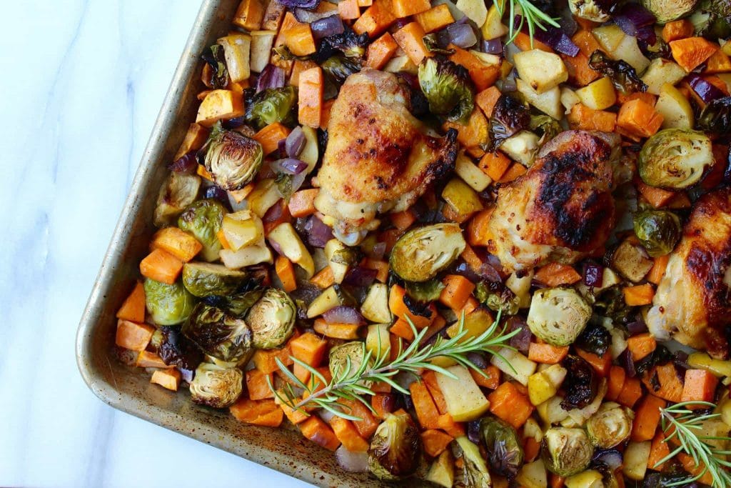 Sheet pan chicken with roasted vegetables and rosemary sprigs.