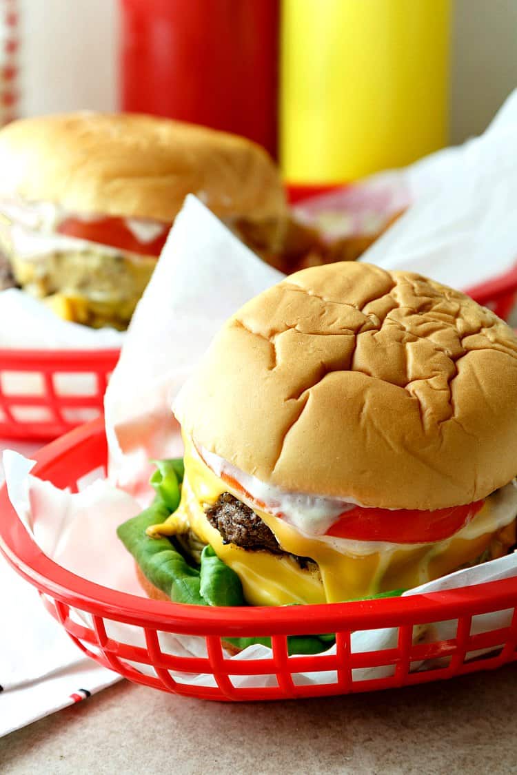 A red basket line with parchment holding a  Double Polar Burger with Everything, just like Danny Zuko ordered at Frosty Palace. 