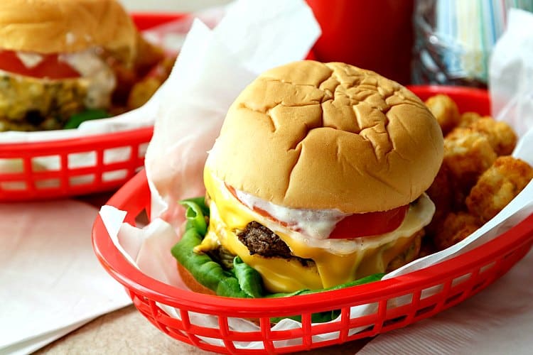 A basket with the  Double Polar Burger with Everything and tater tots. 