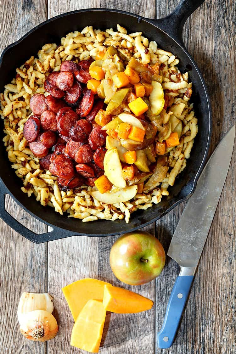 Polish sausage with apples, onions and butternut squash over spaetzle in a cast iron skillet. 