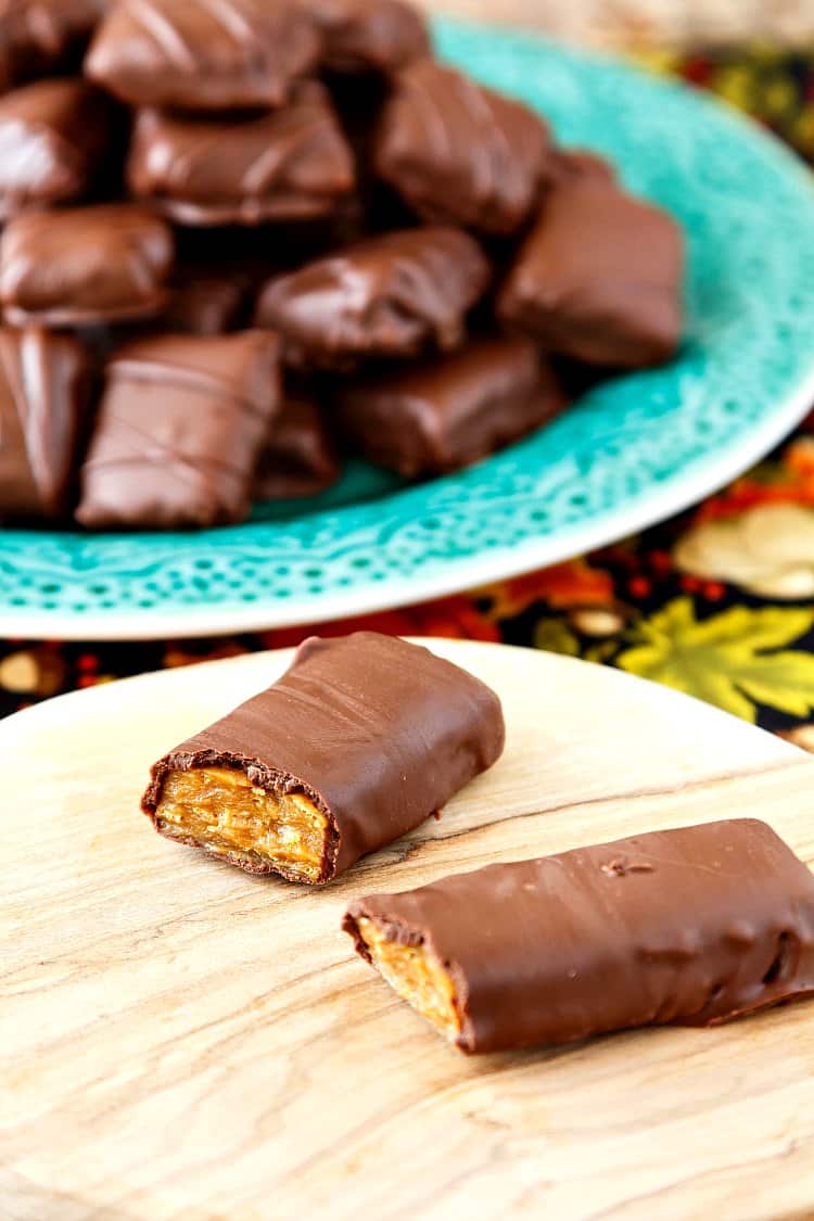 A green plate of chocolate covered candies in the background with a broken homemade butterfinger candy bar in the foreground.