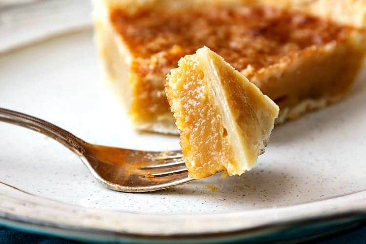 A bite of vinegar pie on a fork with the rest of the slice on a plate.