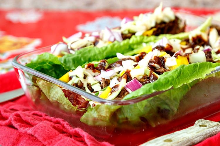 Beef carnitas lettuce wraps in a rectangular glass dish on red cloth.