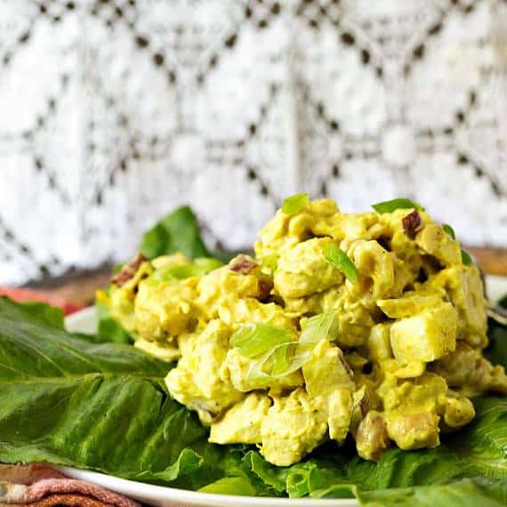 A scoop of curried chicken salad on a lettuce-lined plate.