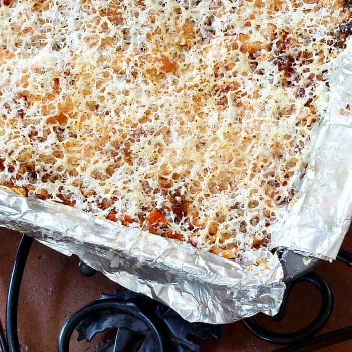 Overhead close up shot of the top of a baked lasagna in a foil-lined loaf pan.