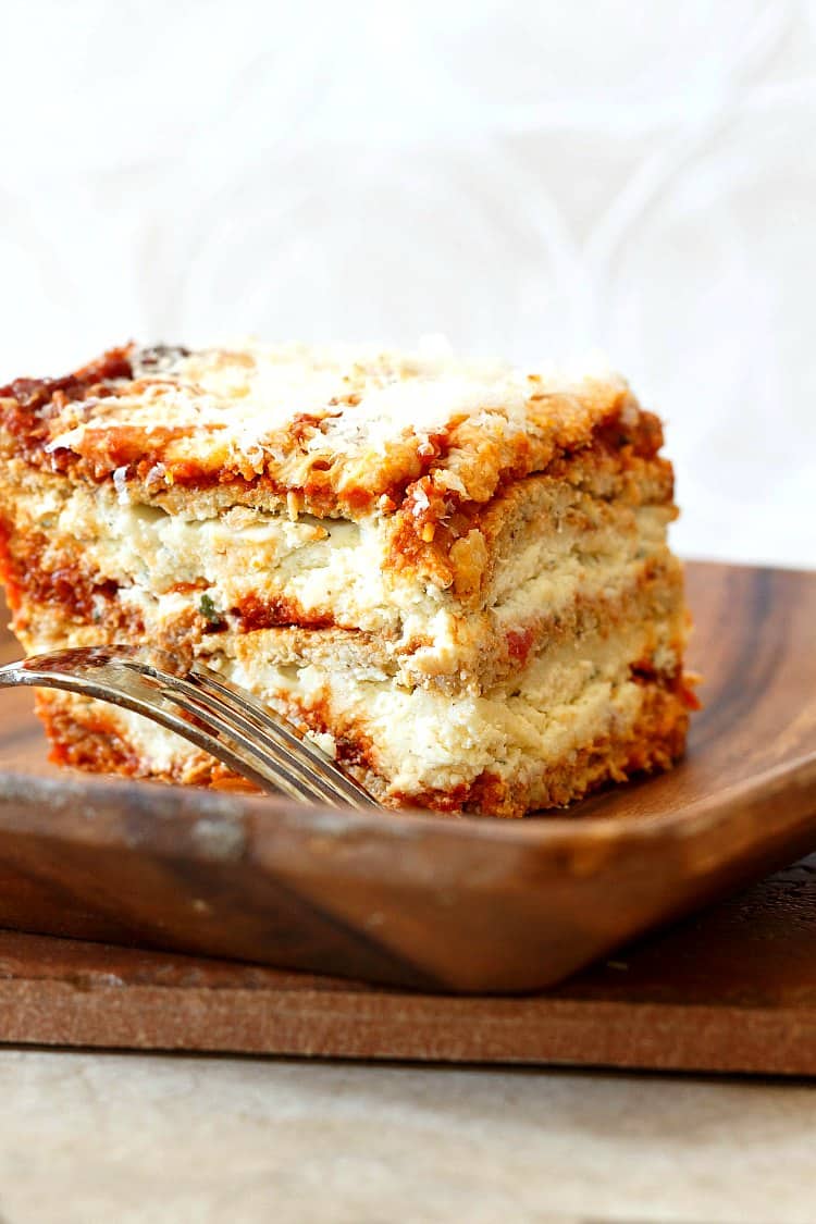 A slice of keto lasagna made with cauliflower noodles on a wooden plate.