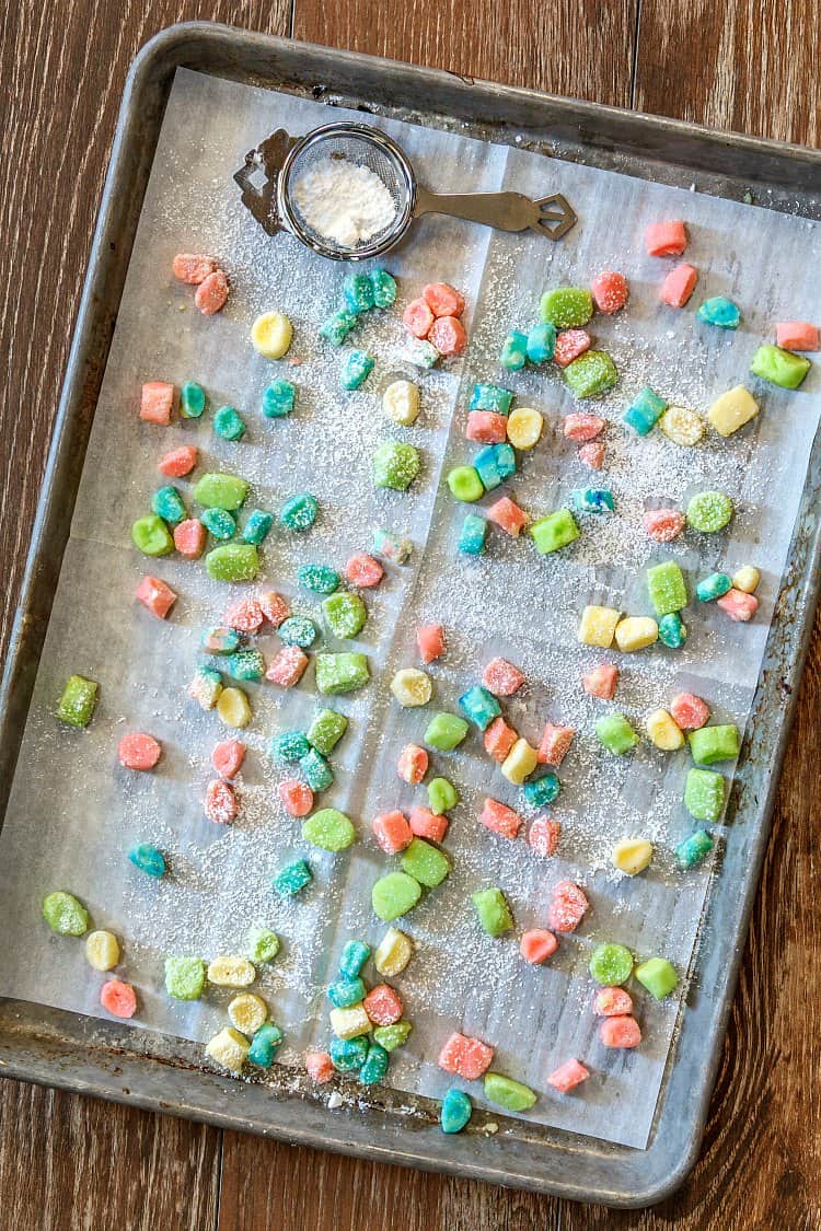 A tray of colored baby shower mints drying on parchment.