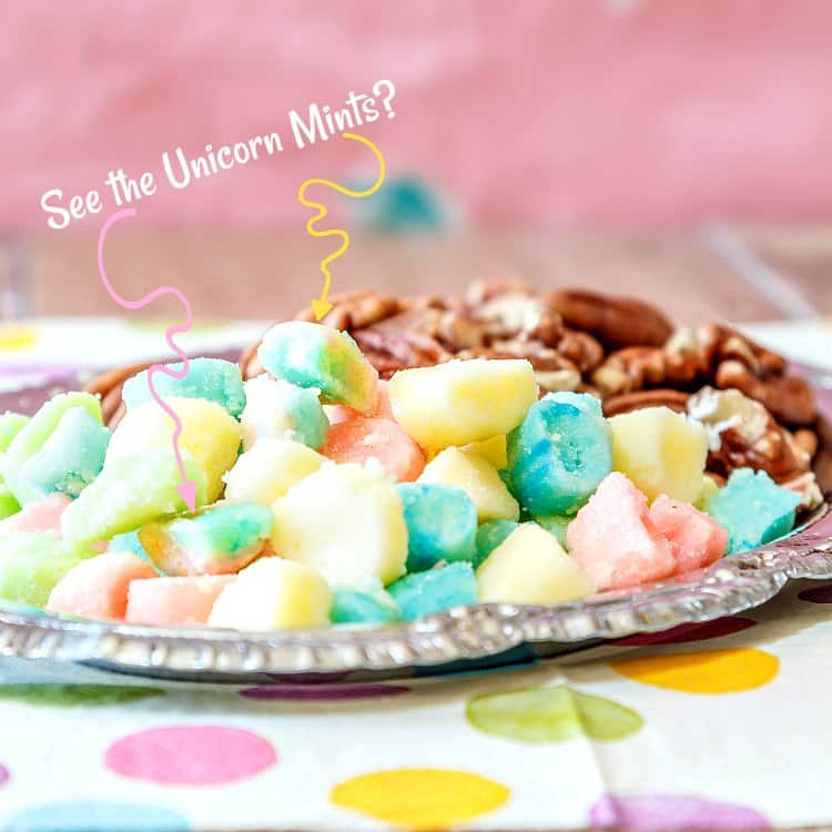 A silver tray of mints and nuts with squiggly arrows pointing to two Unicorn mints. Text reads "See the Unicorn Mints?".