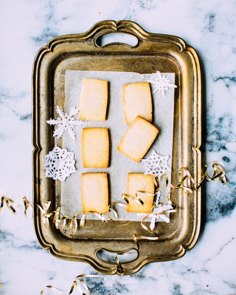 overhead shot of rectangular sable dough cookies on parchment on a tarnished silver tray.