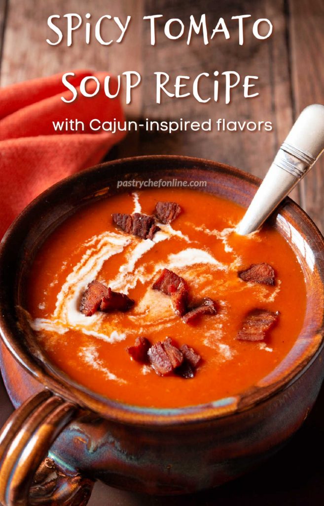 Tomato soup with cream and bacon bits on top. Text reads, "spicy tomato soup recipe with Cajun-inspired spices."