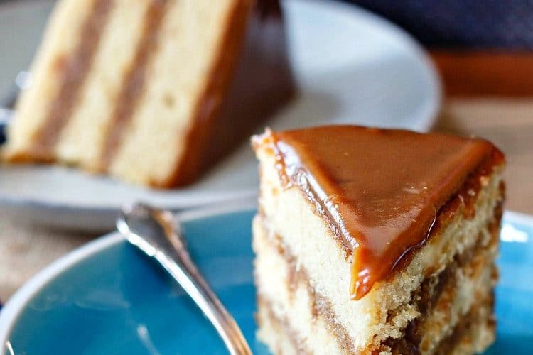 slice of golden 3 layer cake with caramel colored icing
