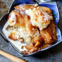 A blue petal bowl filled with golden-brown pasty, spiced peaches, and creamy white dessert sauce.