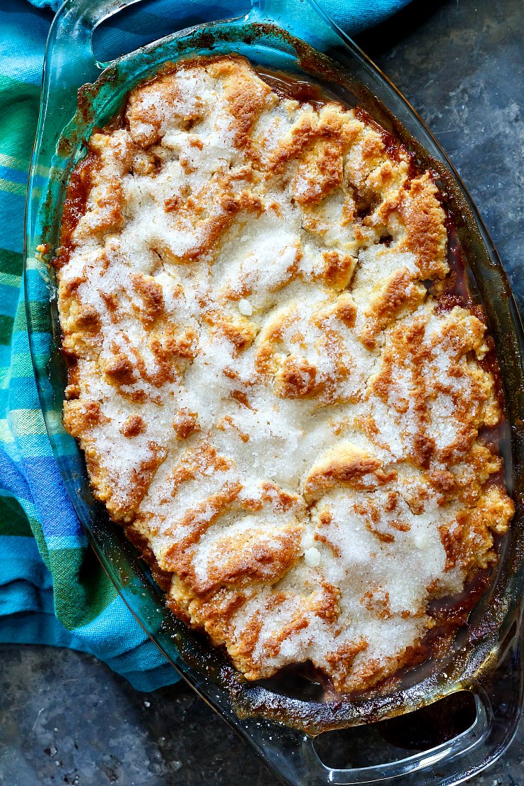 An oval pan of baked lazy peach sonker  with a blue striped napkin.